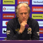 Jorge Jesus speaking at a press conference, standing in front of microphones and a backdrop